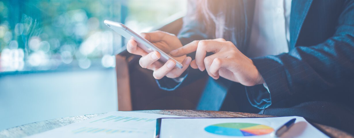 Man sitting at a laptop holding a smartphone 
