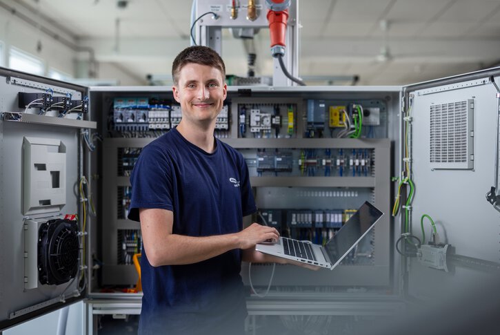 JUMO employee configuring the systems with a laptop in front of the control cabinet