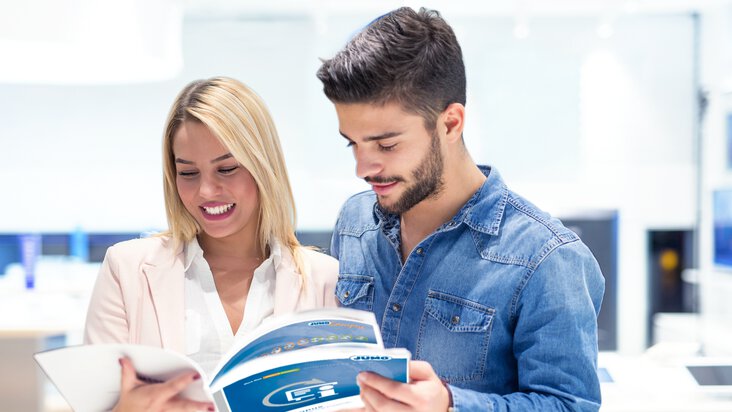 Un homme et une femme regardent dans la brochure JUMO