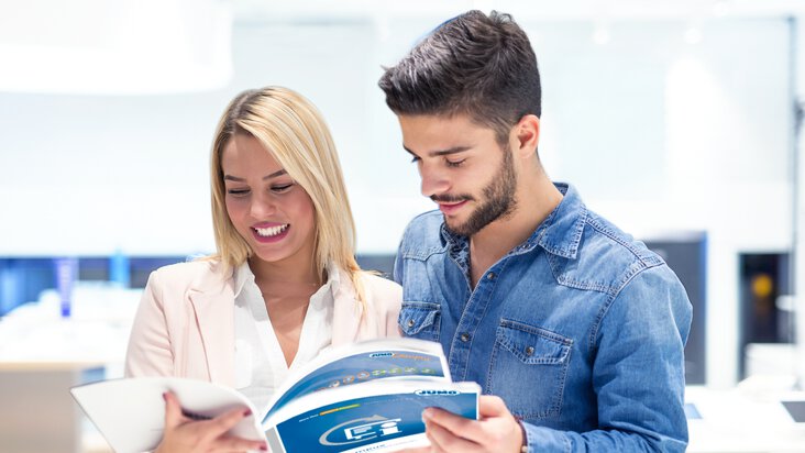 Un homme et une femme regardent dans la brochure JUMO